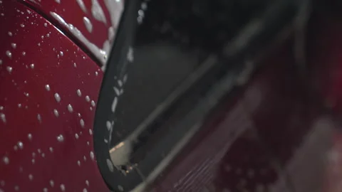 Close up of soap dripping on red car surface during car wash process Stock Footage 310177444