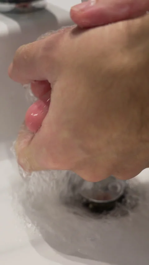 Close up of soapy hands rubbing together and interlacing fingers over a white Stock Footage 347821722