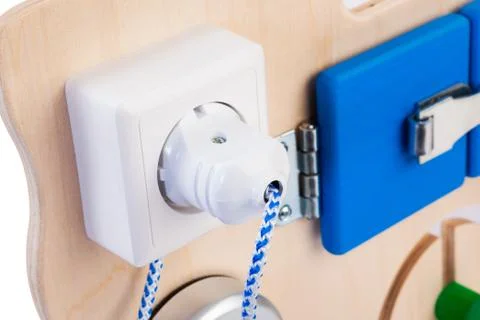 Close-up socket with a plug and wire on a wooden busy board- educational toy  Stock Photos