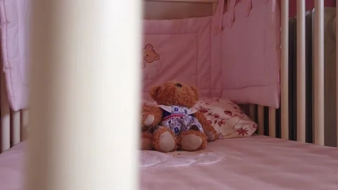 Close up of a soft bear toy at white children's bed. baby cot Stock Footage 148411139