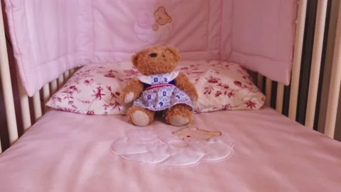 Close up of a soft bear toy at white children's bed. baby cot Stock Footage 148411218