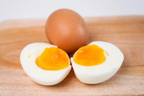 A close-up soft-boiled egg cut into two halves in the foreground and a sing.. Stock Photos