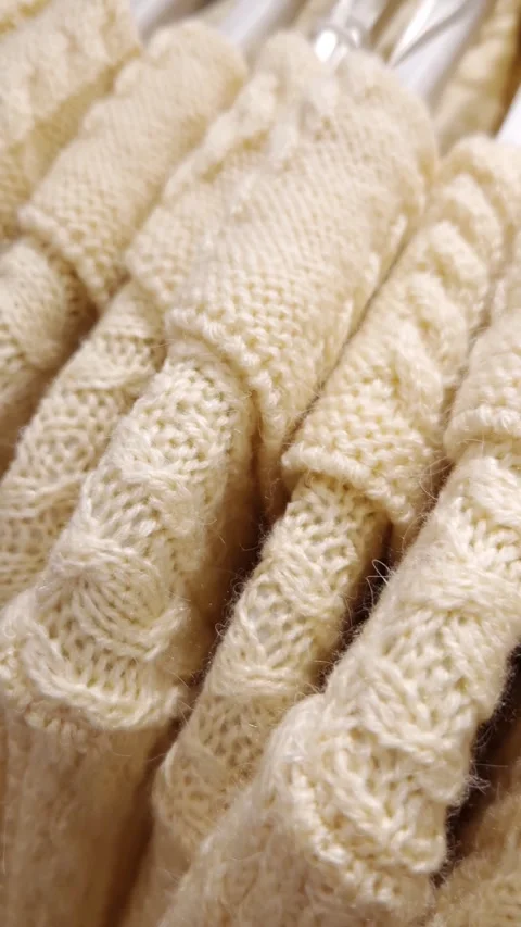 Close-Up of Soft Cream Cable Knit Sweaters on a Rack Stock Footage 326060780