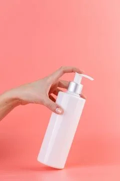 Close-up on a soft pink background white glossy bottle with dispenser minimalist Stock Photos