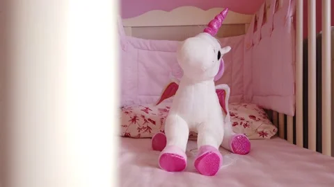 Close up of a soft unicorn toy at white children bed. baby cot Stock Footage 148411044
