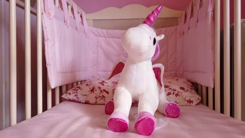 Close up of a soft unicorn toy at white children bed. baby cot Stock Footage 148411069