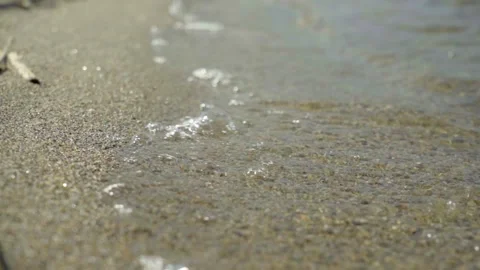 A close-up of the soft waves of lake water lapping the sandy shore. Stock Footage 239983570