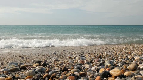 Close-up on soft waves, with white foam crashing on pebble beach Stock Footage 121688688