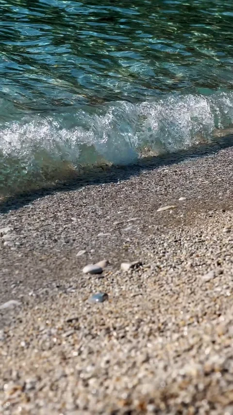 Close-up . soft waves, with white foam are washed ashore, on pebble beach. Stock Footage 321013109