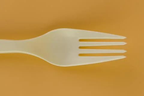 Close up soft yellow background pair of plastic white forks disposable tableware Stock Photos