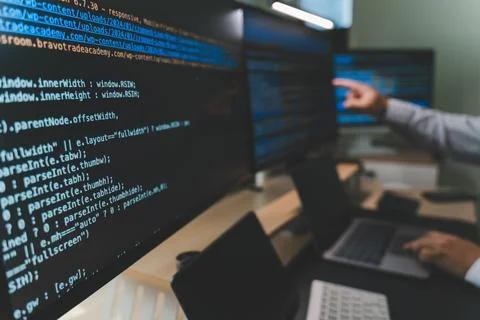 Close up of software engineer working at a multi monitor workstation with c.. 写真素材