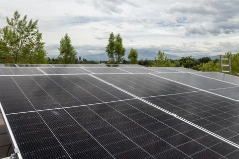 Close-up of solar panels on rooftop with cloudy sky, renewable energy background Stock Photos