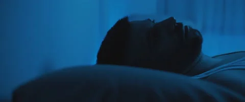 Close up of a soldier lying on bed, staring at the ceiling, dealing with post Stock Footage 147538198