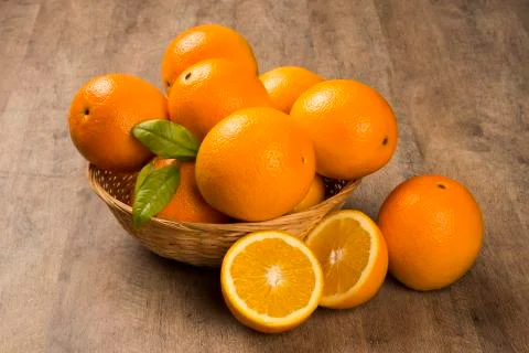Close up of some oranges in a basket over a wooden surface Stock Photos
