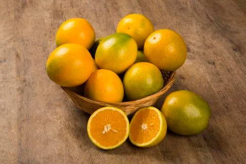 Close up of some oranges in a basket over a wooden surface Foto stock