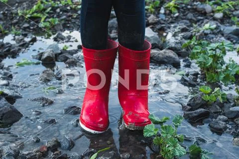 Close-up of some red boots in a puddle formed by the rain. Stock Photos