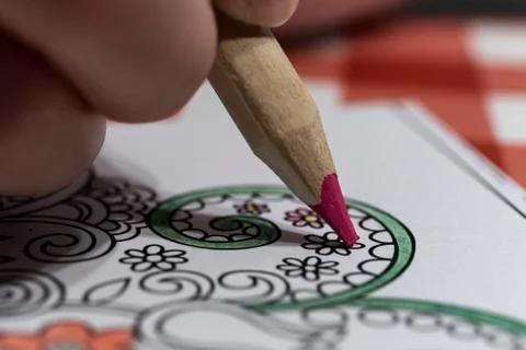 Close-up of someone coloring in a coloring book with a red pencil. An adult c Stock Photos