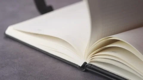 Close up of someone flipping through blank pages of an open notebook on a t.. Stock Footage 333032139