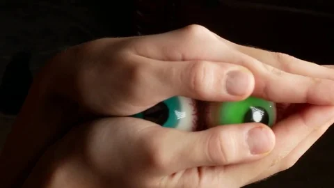 Close-up. Someone hides in the palms of large round candy, similar to the eyes Vídeo Stock 85066944