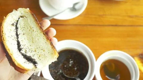 Close-up, someone spreads fig jam on a slice of roll with poppy seeds. Vidéo 116133991