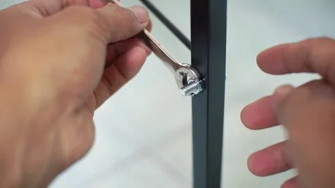 Close-up of someone using a screwdriver to assemble metal and wood furniture. Stock Footage 325352880