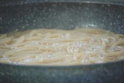 Close up of spaghetti boiling with active bubbles and foam in a dark textur.. Foto stock