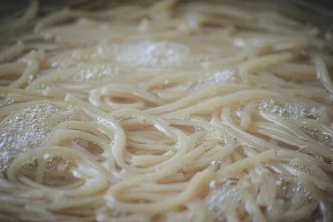 Close up of spaghetti boiling with active bubbles and foam in a dark textur.. Foto stock