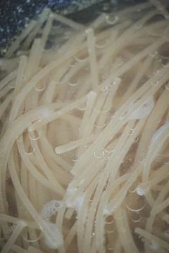 Close up of spaghetti boiling in water with bubbles and foam during the coo.. 库存照片