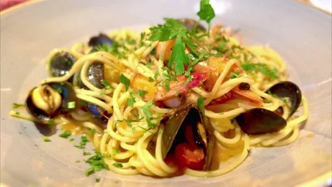 Close up of spaghetti dish with seafood platter of cod prawns mussels and onion 動画素材 325050747