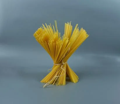 Close-up of spaghetti tied with thread on a gray background. Stock Photos