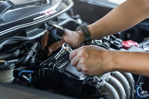 Close up spark plug coil on engine cover and a man use block wrench remove .. Foto stock