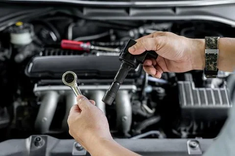 Close up spark plug coil in hand a man and use block wrench remove a bolt i.. Stock Photos