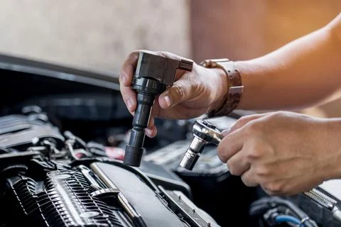 Close up spark plug coil in hand a man and use block wrench remove a bolt i.. Stock Photos
