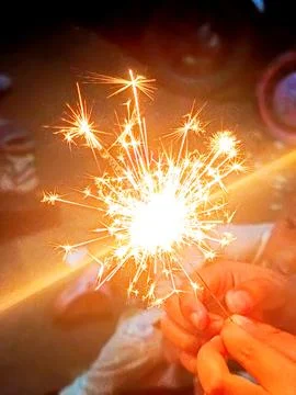 Close Up Sparkler Firework in Hands at Night with Bright Golden Sparks Photos