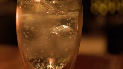 Close Up of Sparkling Drink with Ice in Warm Candlelight Stock Footage 326080443