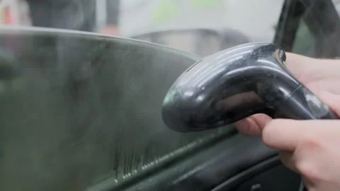 Close-up of a specialist's hands carefully removing old tint film from a car 스톡 동영상 337537892