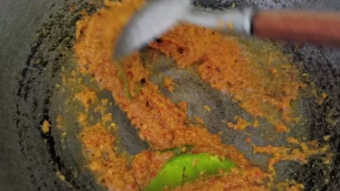 Close up of spicy red chili paste being stirred with lime leaves in a hot metal Stock Footage 330517239