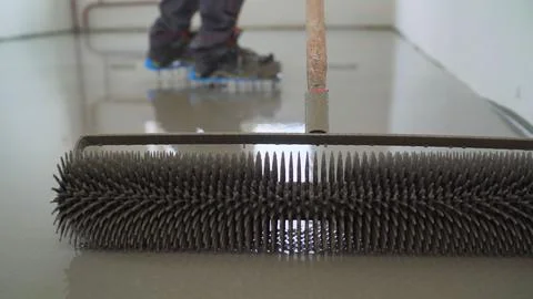 Close up of spiked roller for self leveling floor with construction worker .. Stock Photos