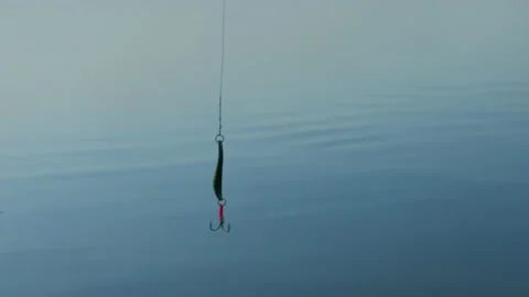 Close-up of a spinner and a hook on the background of water. Morning fishing Stock Footage 219776431