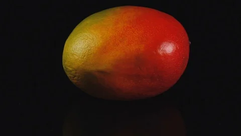 Close up of spinning mango on a black mirror table. Stock Footage 113265260
