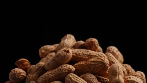 Close up of spinning pile of peanuts isolated black background Stock Footage 275489414