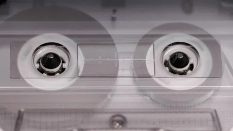 Close-up of spinning reels inside compact cassette in a vintage tape recorder Stock Footage 303138648