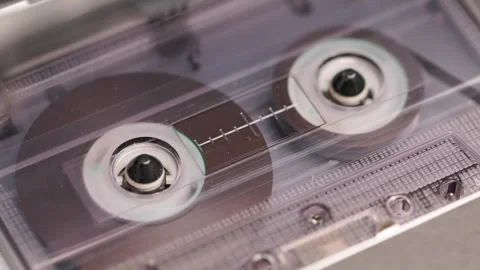 Close-up of spinning reels inside compact cassette in a vintage tape recorder Stock Footage 303138657
