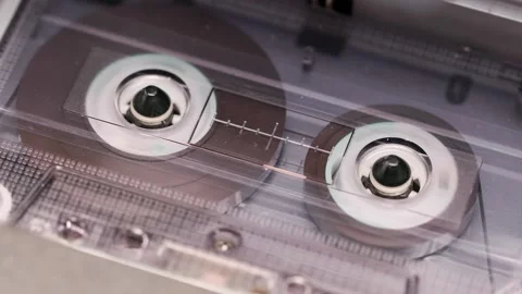Close-up of spinning reels inside compact cassette in a vintage tape recorder Stock Footage 303138691