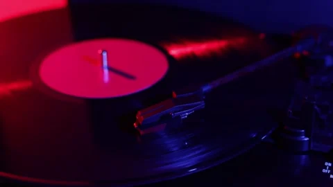 Close-up of a spinning vinyl record with dramatic red and blue lighting Stock Footage 339002304