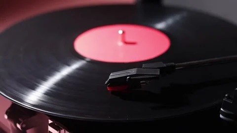 Close-up of a spinning vinyl record with a red label and stylus Stock Footage 339001621