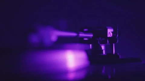Close-up of spinning vinyl record with stylus under pulsating disco lights,.. Stock Footage 310723722