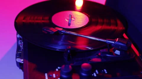 Close-up of a spinning vinyl record on a turntable with red and blue lighting Stock Footage 339002498