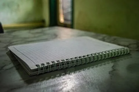 Close up of a spiral notebook with lined paper on a table. The notebook is .. 스톡 사진