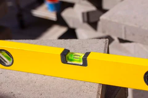 Close up of spirit level placed on stack of outdoor pavers or tiles Stock Photos